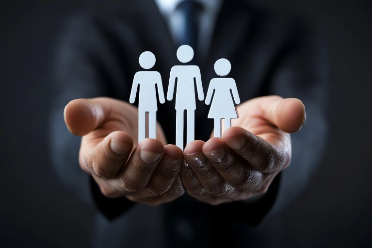 MMCT Well being training illustrating a pair of a business mans cupped hands holding 3 paper cut people 