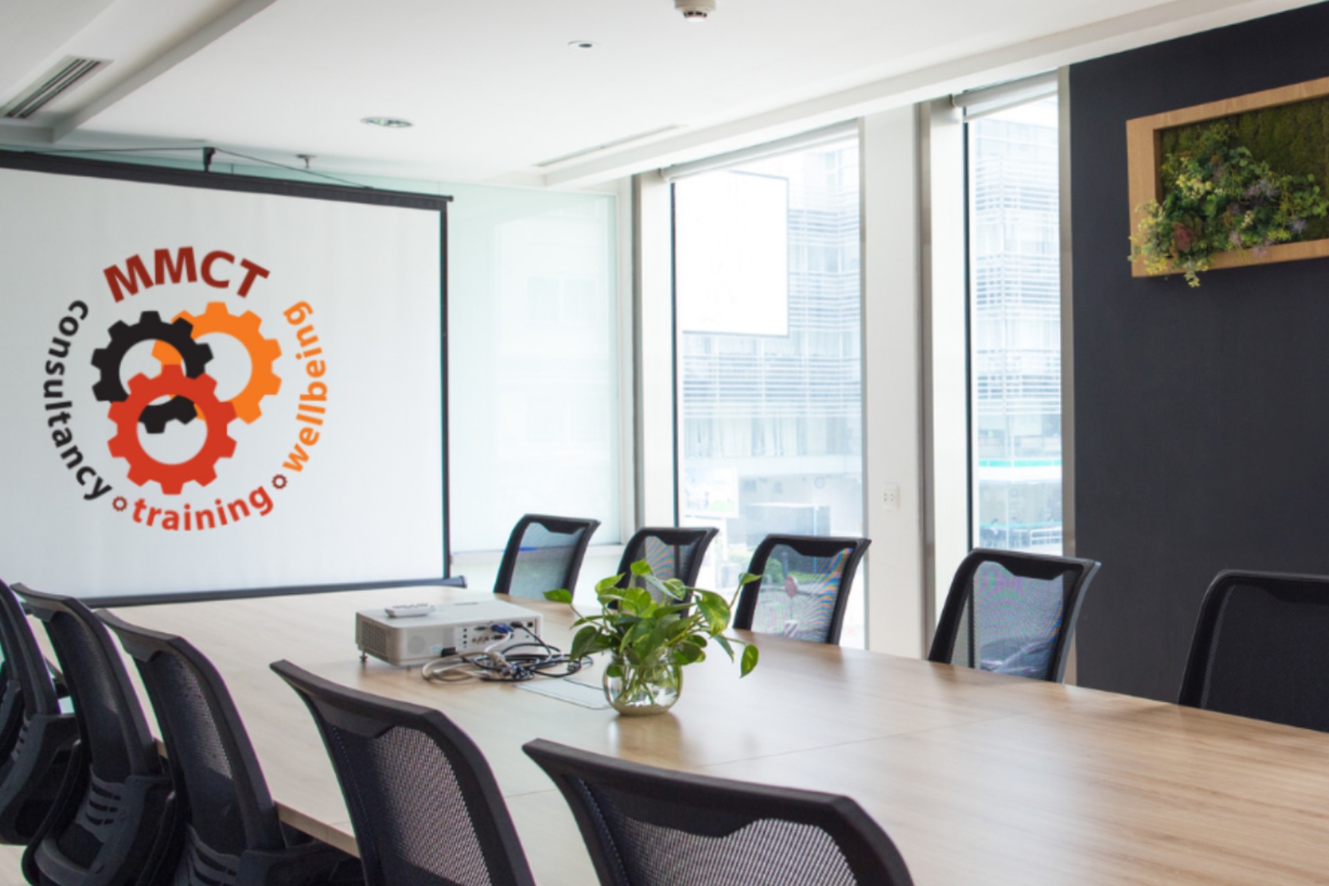 Board room featuring a long table with chairs around it, a white board on the wall featuring the MMCT logo
